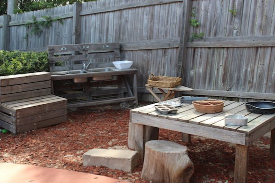 Outdoor daycare play area with sink and wooden table